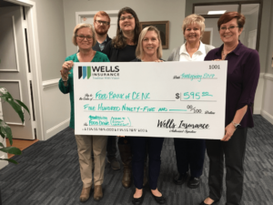 Wells Insurance staff holding a check for the food bank
